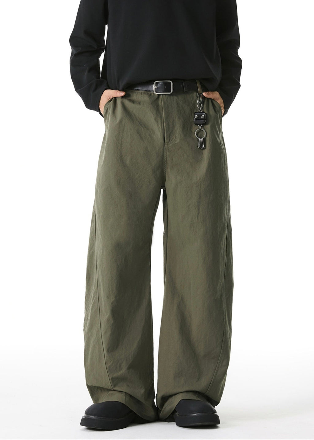 Person wearing olive green wide-leg pants with a black shirt on a white background