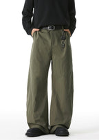 Person wearing olive green wide-leg pants with a black shirt on a white background