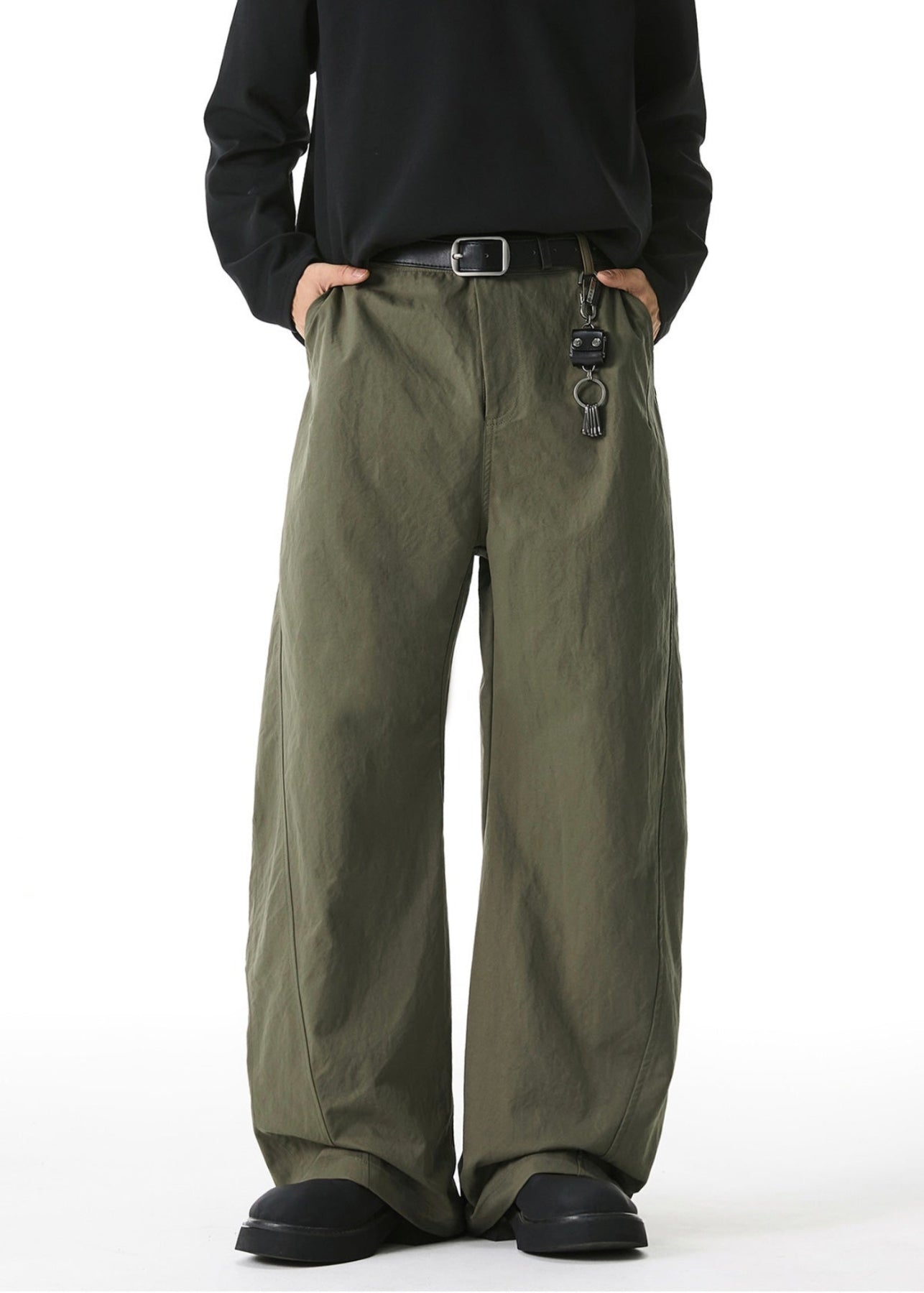 Person wearing olive green wide-leg pants with a black shirt on a white background